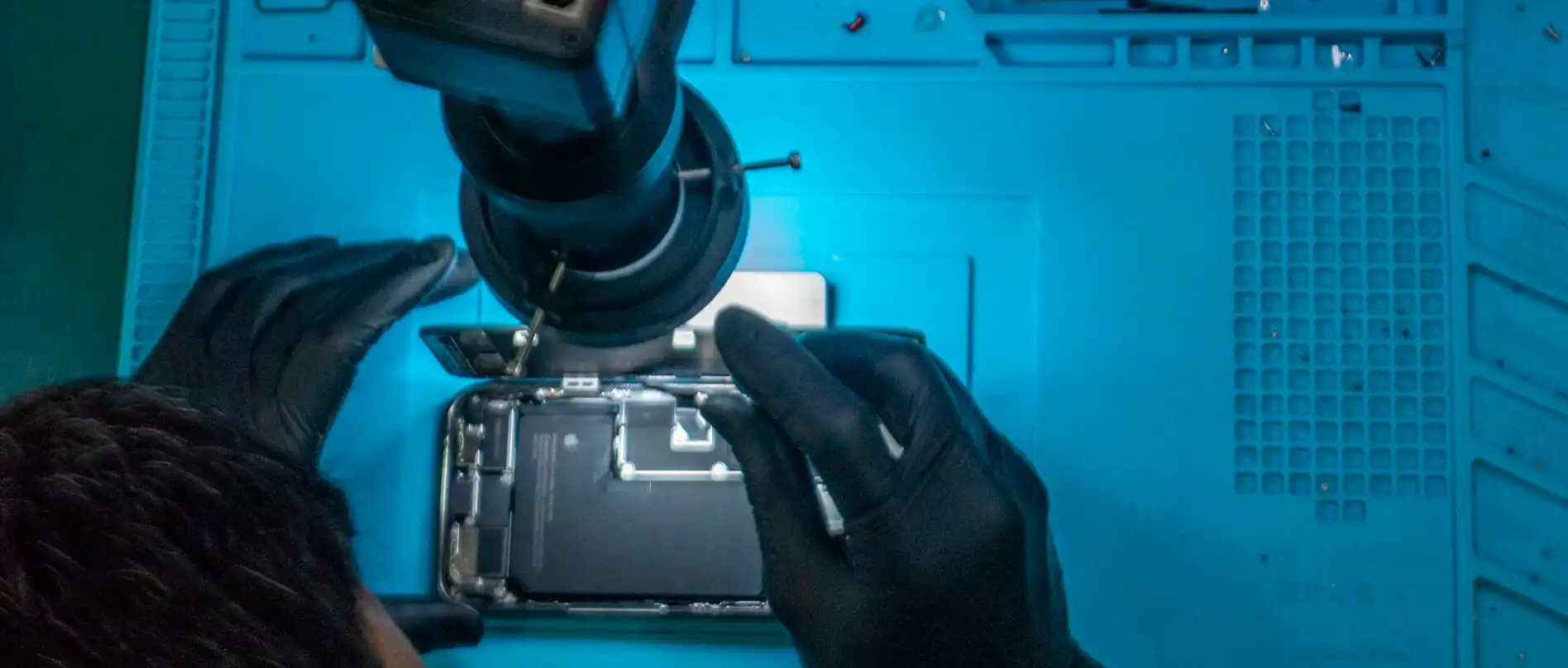 Verificação de bateria de iPhone sob microscópio na bancada da iTelas