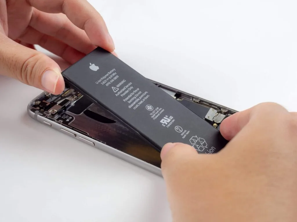 Técnico da iTelas trocando a bateria de um iPhone na bancada
